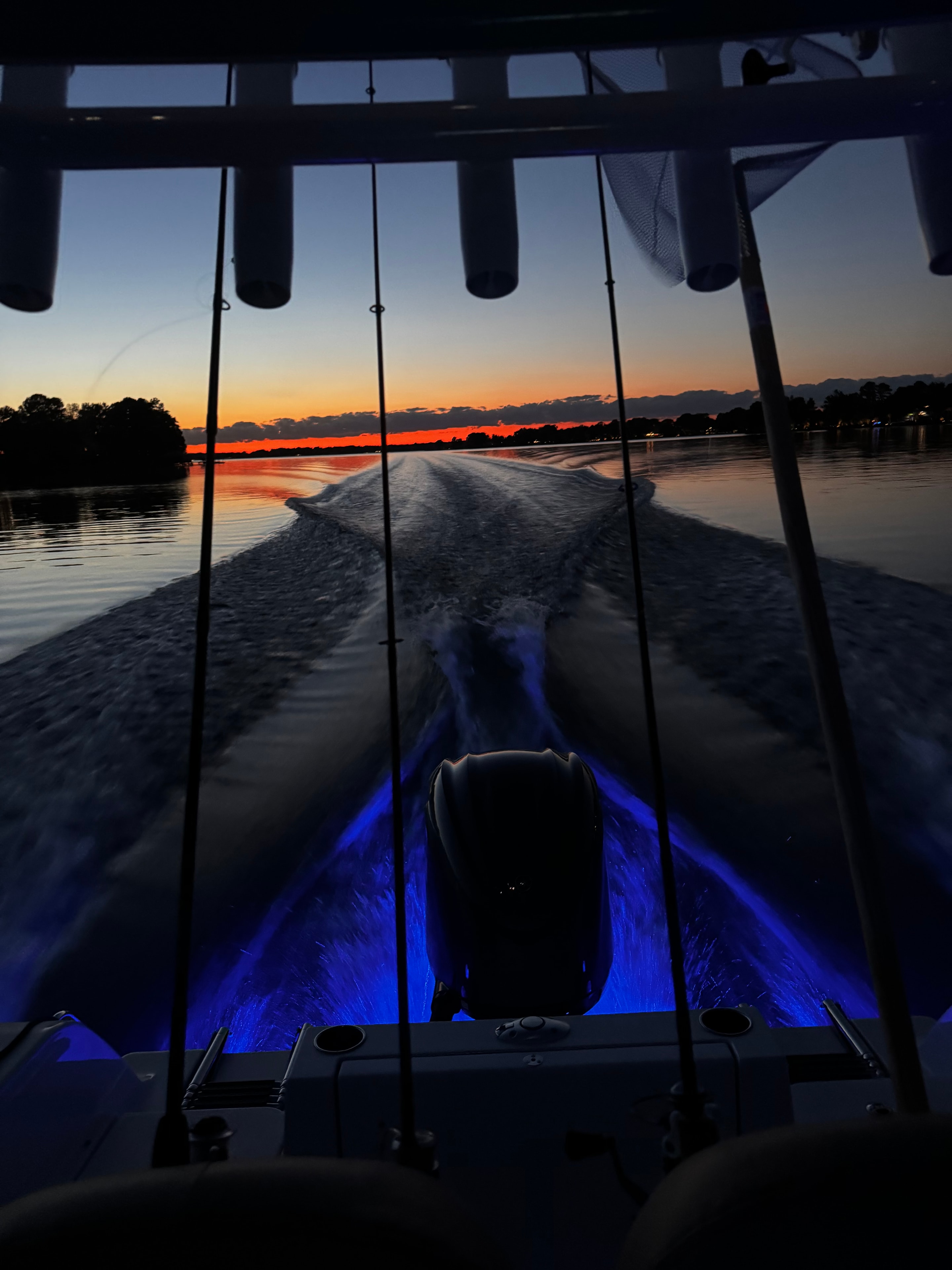 Boat blue accent lights glowing against a deep red sunset horizon