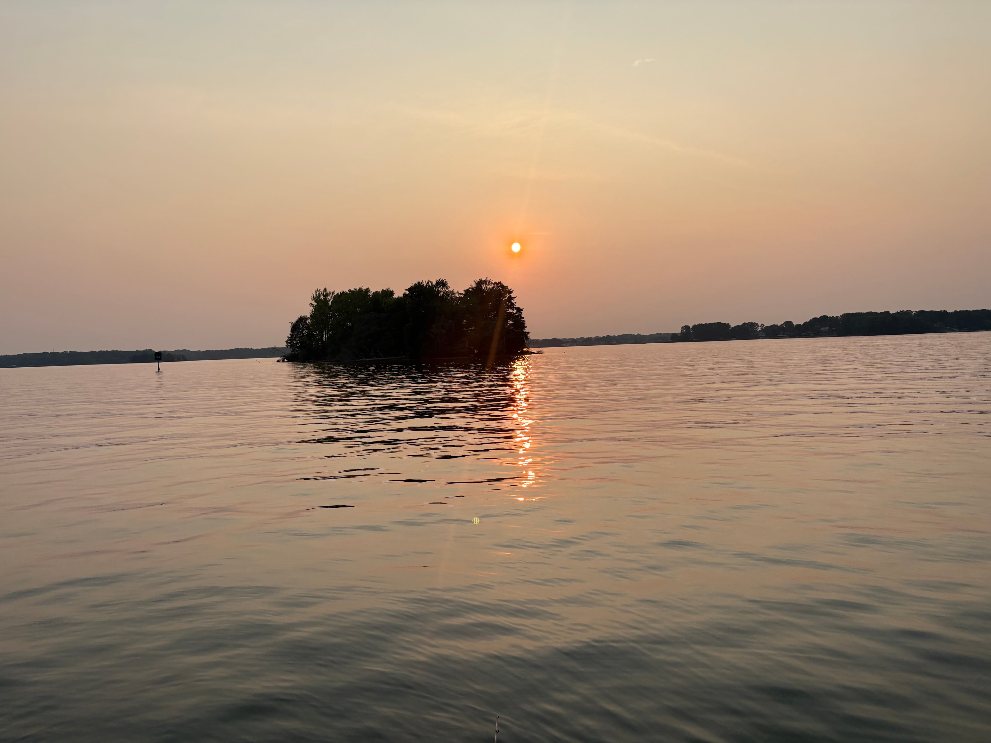 Small island silhouetted against a pink Lake Norman sunset