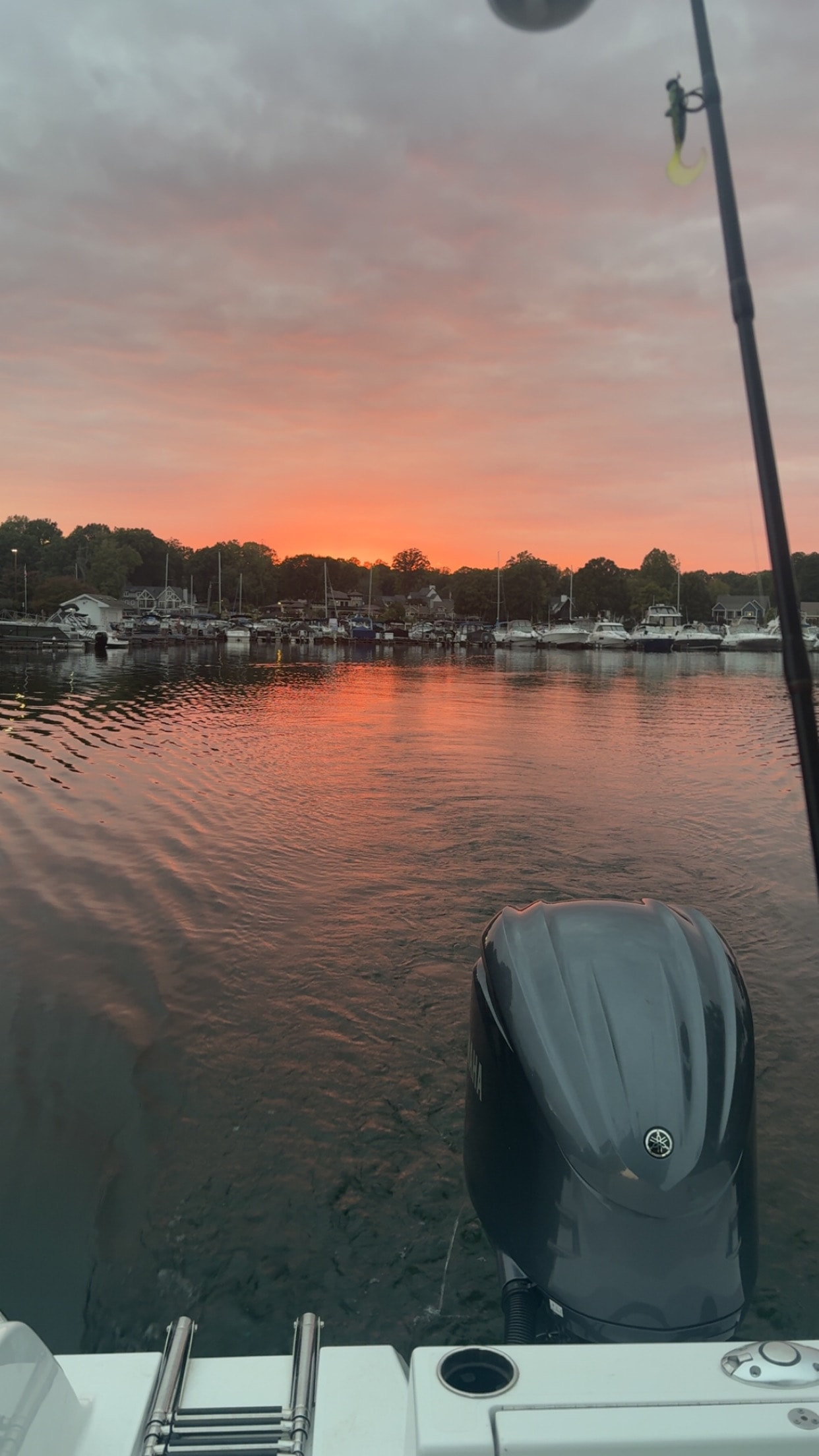 Pink and orange sunset sky over Lake Norman marina with fishing rod