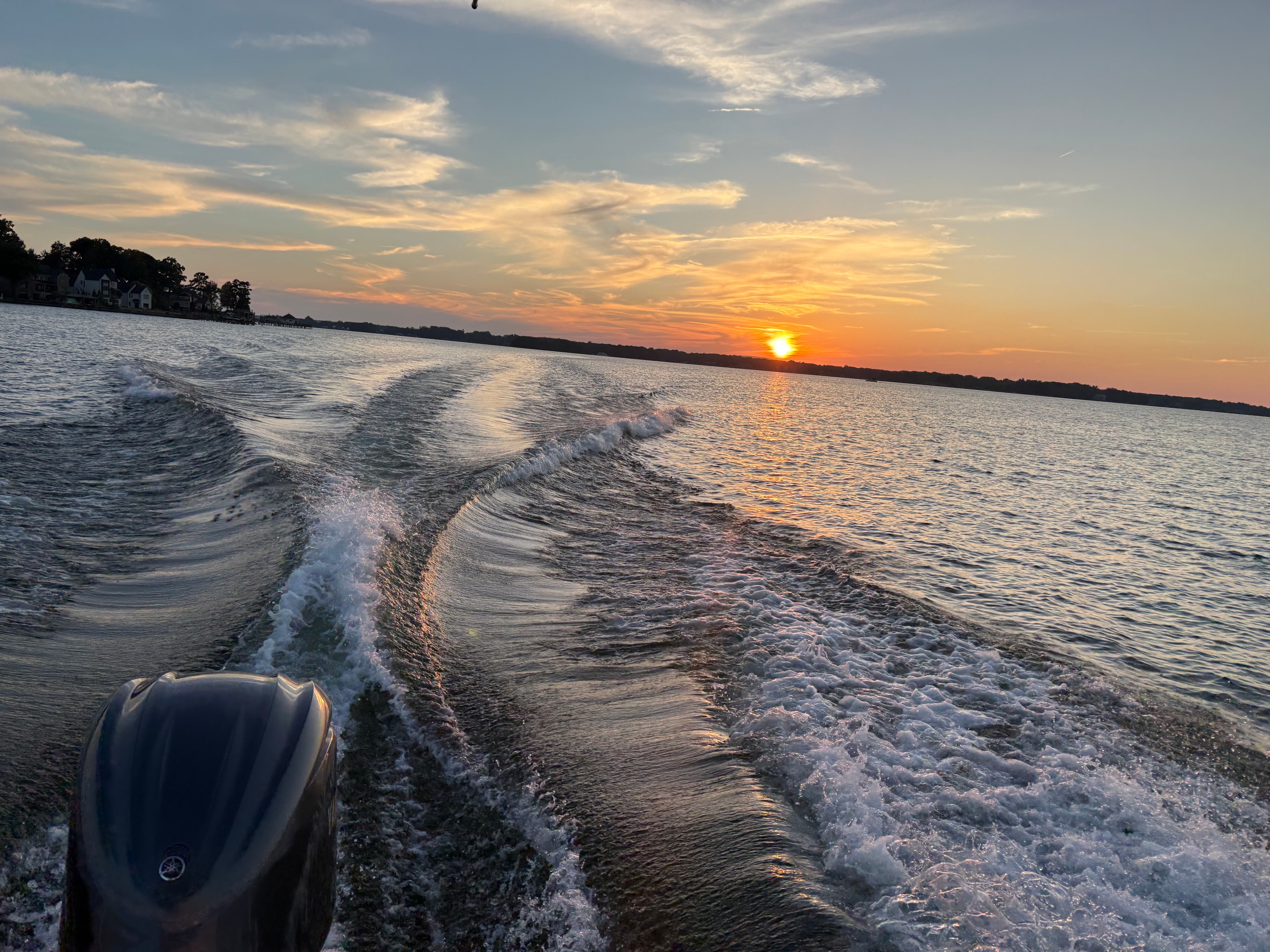 Boat wake glowing in orange sunset light on Lake Norman
